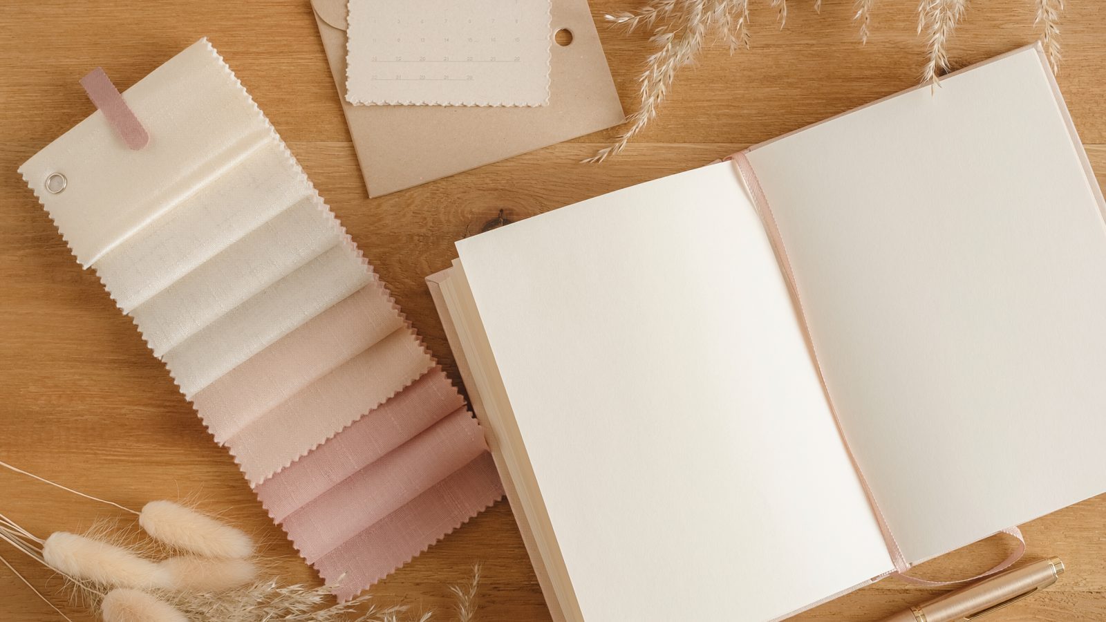 Schreibtisch einer Hochzeitsplanerin mit Planer, Stoffmustern und Kalender von oben