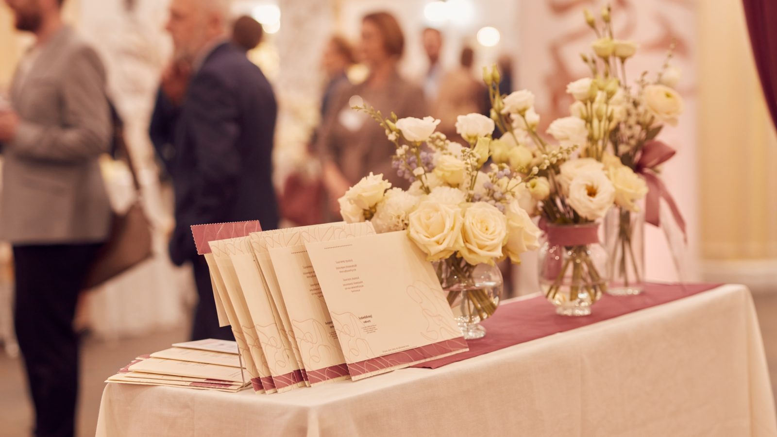 Eleganter Messestand mit Blumendeko auf einer Hochzeitsmesse, Besucher unscharf