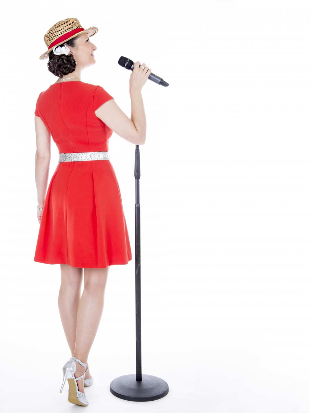 Brautjungfer in rotem Kleid singt bei der Hochzeitsfeier neben einem Mikrofonständer, zurück zur Kamera gewandt.