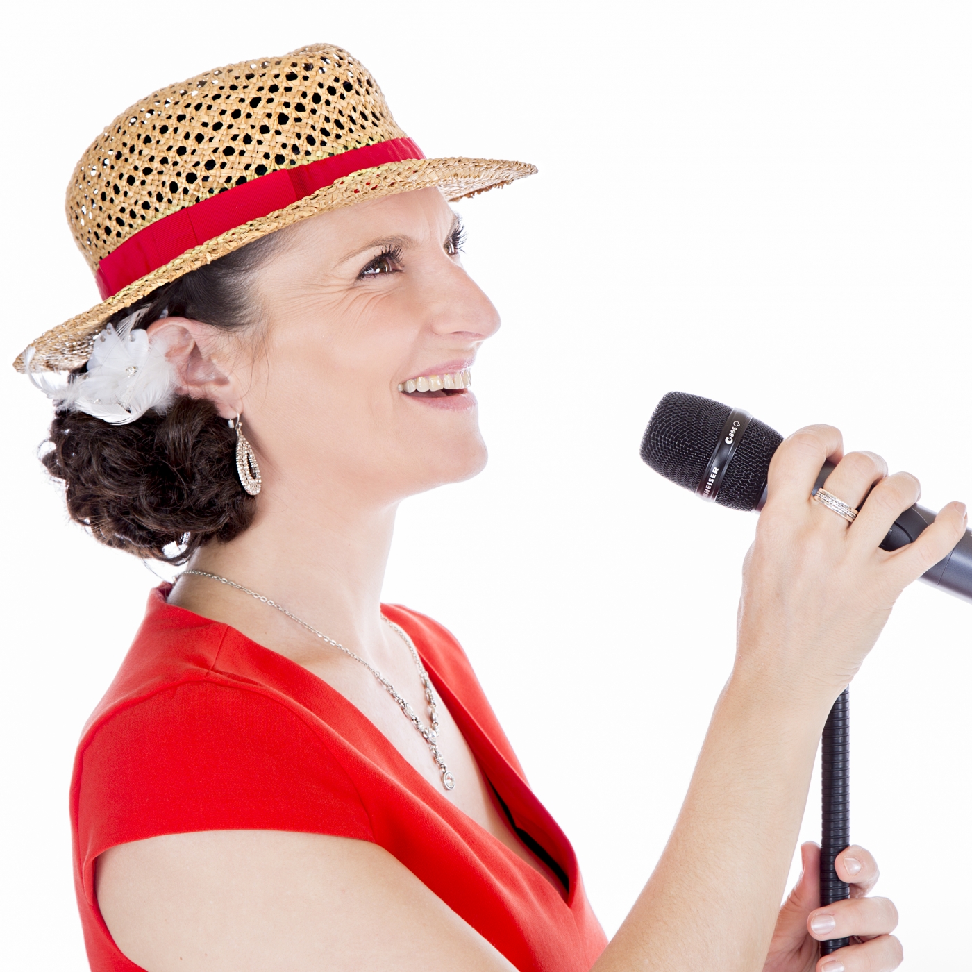 Sängerin auf einer Hochzeit mit Mikrofon in der Hand singt, trägt ein rotes Kleid und einen Strohhut.
