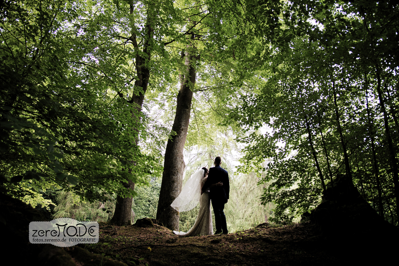 Braut und Bräutigam stehen bei ihrer Hochzeit im Wald, umgeben von Hochzeitsdekoration und Bäumen.