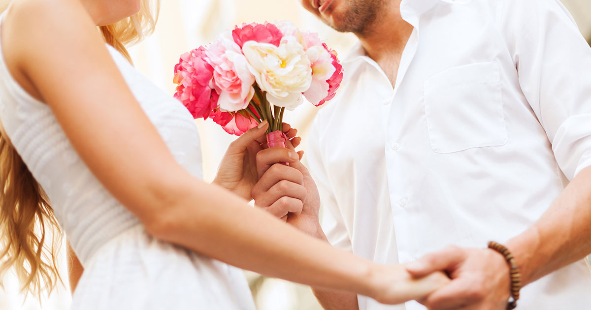 Nahaufnahme von Braut und Bräutigam, die sich an den Händen halten und einen Blumenstrauß aus Hochzeitsblumen halten