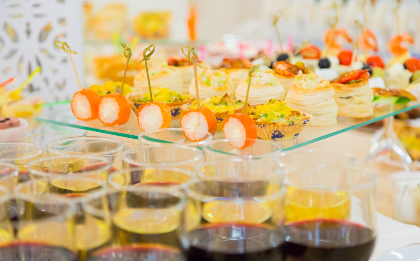 Gläser mit Wein und Sekt, dekorative Canapés und Snacks auf einem Hochzeitsbuffet.