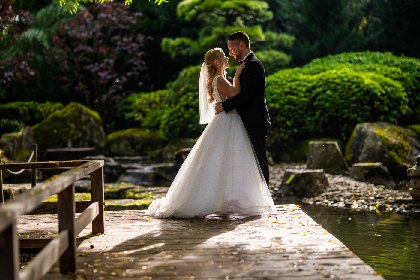 Braut und Bräutigam im Hochzeitsoutfit in Gartenlocation, umgeben von Hochzeitsdekoration und Blumen