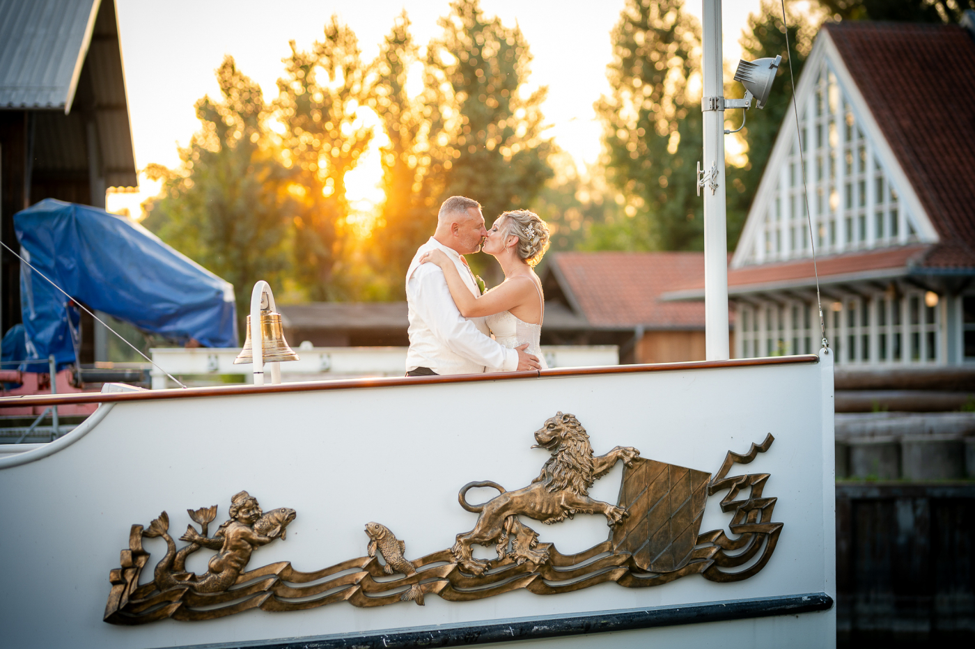 Braut und Bräutigam auf einem dekorierten Boot bei Sonnenuntergang, umgeben von romantischer Hochzeitsatmosphäre.