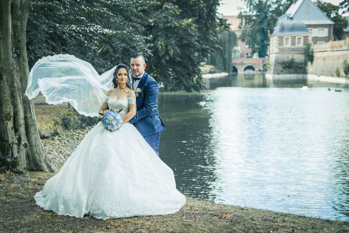 Braut und Bräutigam in eleganter Hochzeitskleidung an einem See. Romantische Hochzeitsfotografie und malerische Hochzeitslocation.