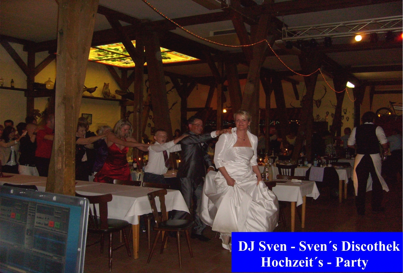 Braut und Bräutigam feiern im rustikal dekorierten Festsaal mit Gästen bei der Hochzeitsparty. Hochzeitsfotografie, Eheringe, Hochzeitstorte umranden die fröhliche Feier.
