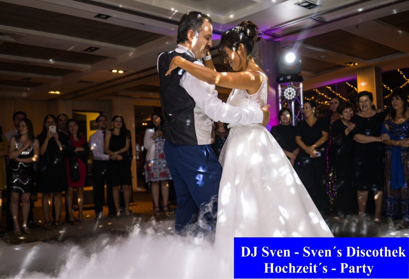 Braut im Hochzeitskleid und Bräutigam tanzen ihren Eröffnungstanz während der Hochzeitsfeier, umgeben von Gästen.