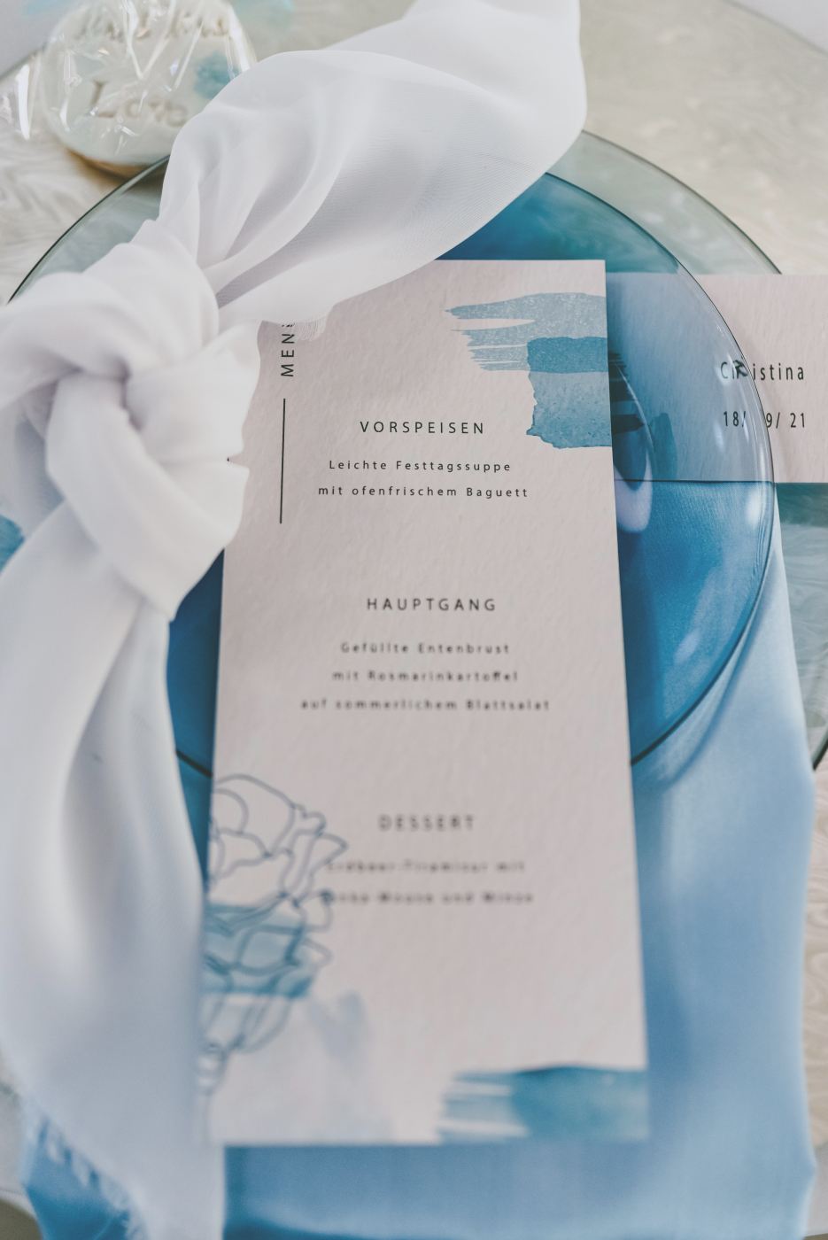 Detailaufnahme einer stilvollen Tischdekoration bei einer Hochzeit mit personalisierter Menükarte und Serviette.
