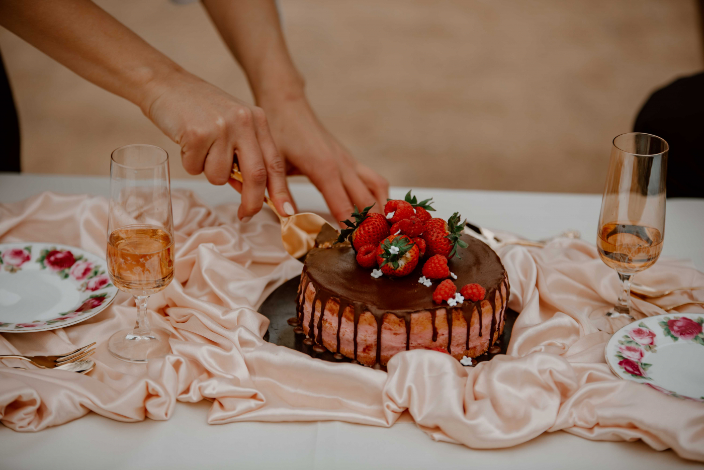 Brautpaar schneidet Hochzeitstorte an, umgeben von Hochzeitsblumen und Hochzeitsdeko auf der Hochzeitsfeier.