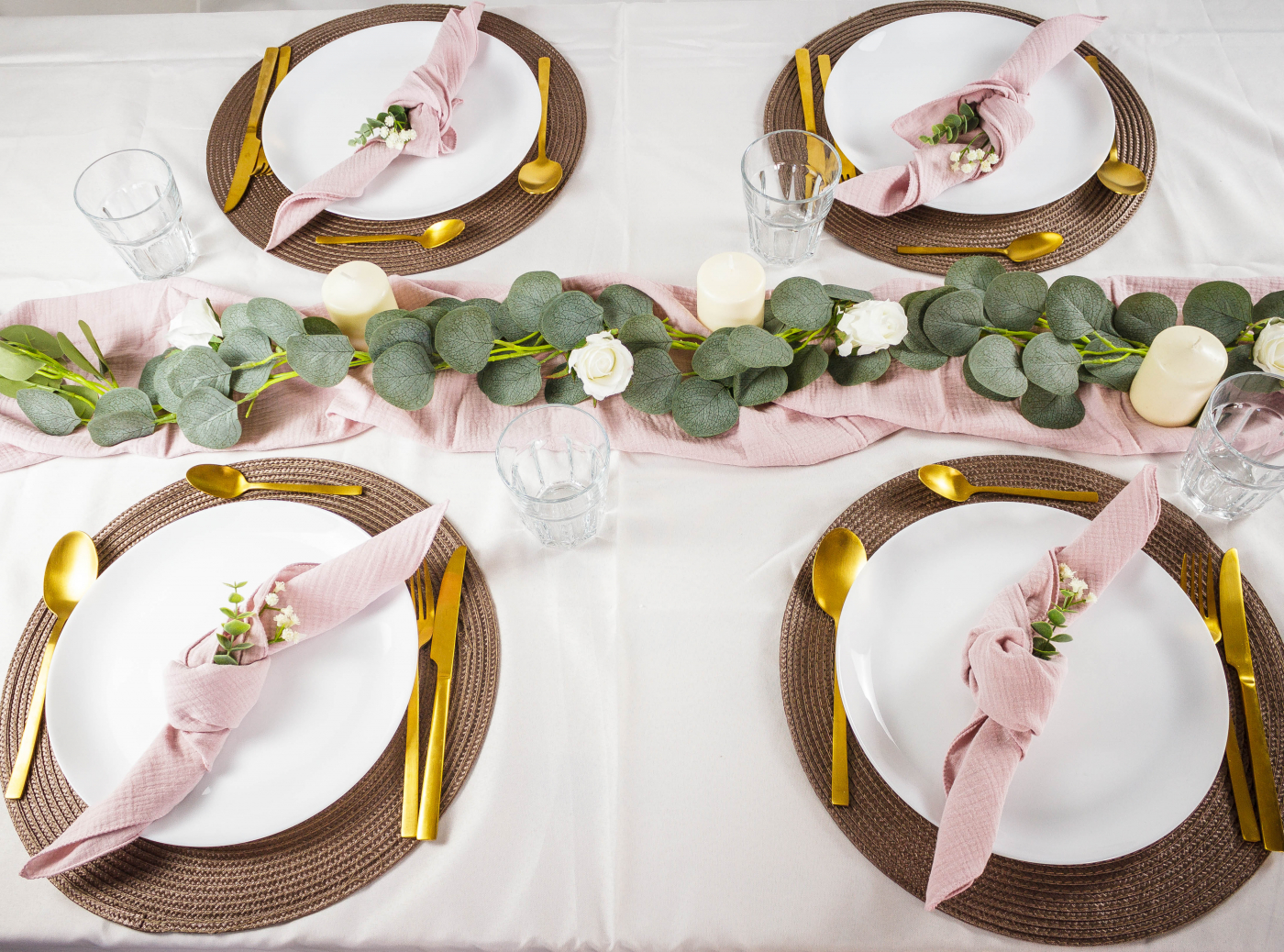 Schöne Tischdekoration für die Hochzeitsfeier mit rosa Servietten, frischen Blumen und goldenen Bestecken.