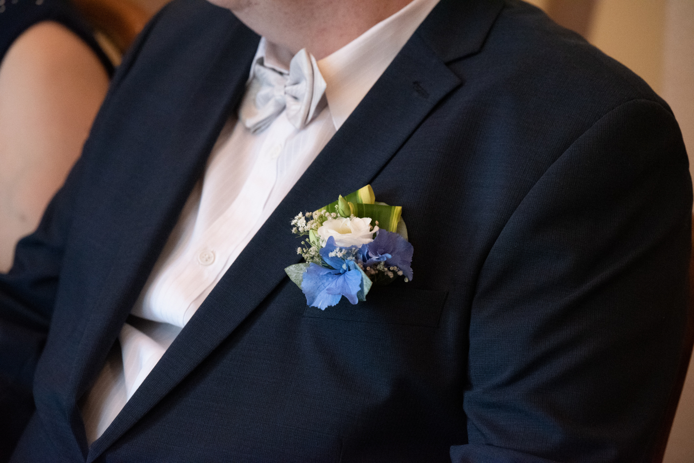 Braut und Bräutigam während der Hochzeitszeremonie, Bräutigam trägt Anzug mit weißer Boutonniere.