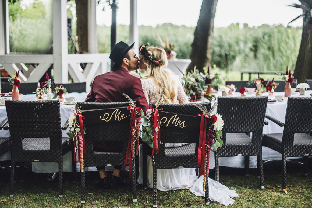 Braut und Bräutigam sitzen vor der Hochzeitslocation in eleganter Hochzeitsdekoration, umgeben von Hochzeitsblumen.