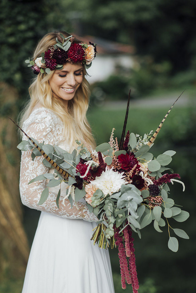 Braut in Hochzeitskleid mit Blumenstrauß, lächelnd in malerischer Hochzeitslocation; Hochzeitsplanung, Hochzeitsfotografie.