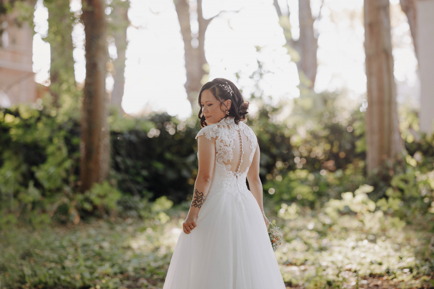 Braut in einem weißen Hochzeitskleid steht bei der Trauung im Wald. Hochzeitsfotografie und Hochzeitsdekoration.